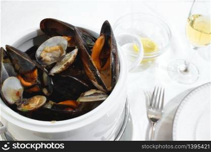 Pot of mussels and clams on a table with white tablecloth in a restaurant