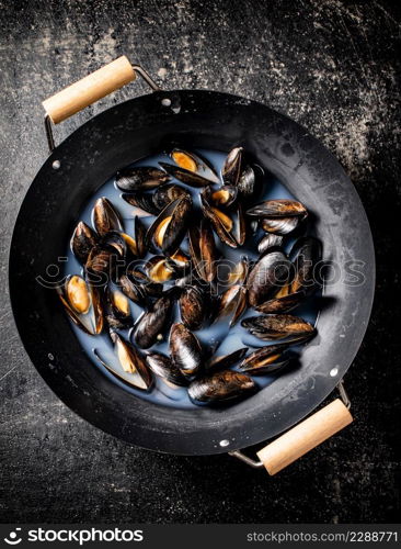 Pot of mussels on the table. On a black background. Top view. High quality photo. Pot of mussels on the table.