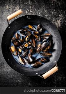 Pot of mussels on the table. On a black background. Top view. High quality photo. Pot of mussels on the table.