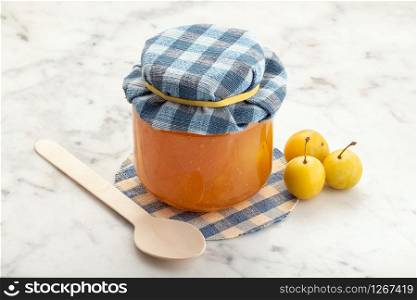 Pot of plum jam and fruit on white marble. Preserved fruits