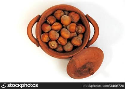 pot with hazelnuts, pine nuts surrounded, isolated, close-up, top view