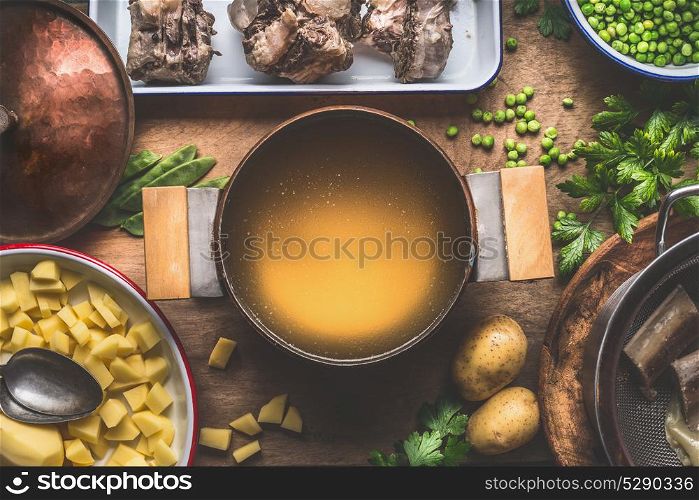 Pot with meat broth , cooking preparation for potatoes soup with green peas, top view