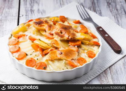 Potato and carrot gratin with herbs in bowl