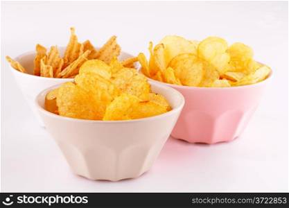 Potato and wheat chips in bowls isolated on gray background.