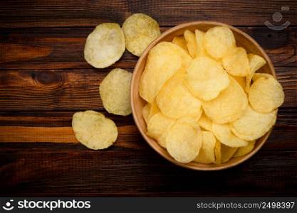 Potato chips in ceramic bowl on dark wooden table