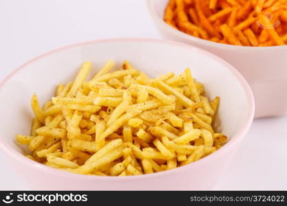 Potato chips in pink and beige bowls isolated on gray background.