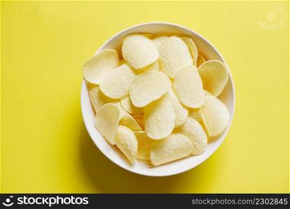 Potato chips snack on bowl and yellow background, Crispy potato chips on the kitchen