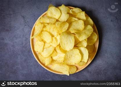 Potato chips snack on plate, Crispy potato chips on the kitchen table black background - top view