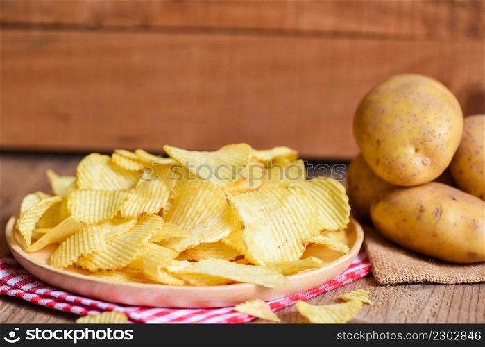 Potato chips snack on white plate, Crispy potato chips on the kitchen table and fresh raw potatoes