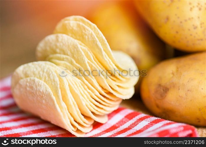Potato chips snack stacked, Crispy potato chips on the kitchen table and fresh raw potatoes
