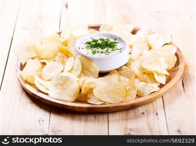 Potato chips with sauce on wooden table