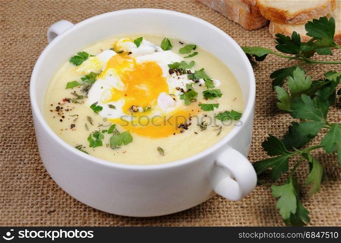 potato cream soup with bacon and poached eggs, herbs, spices