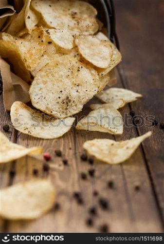 Potato crisps crunchy chips with black pepper in steel snack bucket on wooden table background. Top view