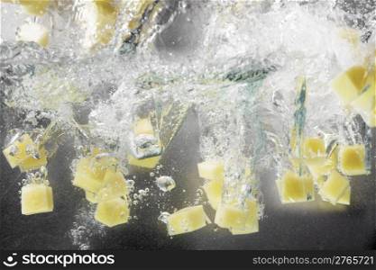 Potato cubes splashing into water.