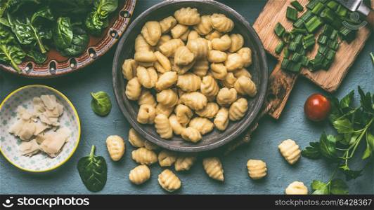 Potato gnocchi with vegetarian cooking ingredients: spinach and vegetables on rustic table , top view