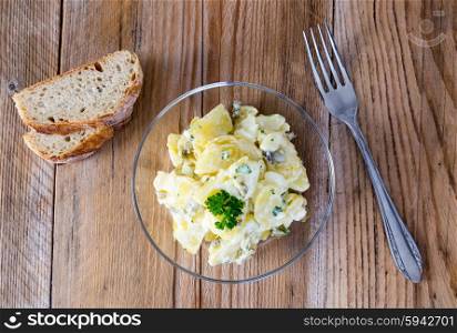 Potato salad in a glass bowl on wooden board. Potato salad in a glass bowl on wooden board.