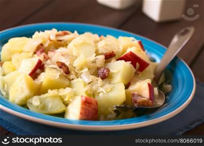 Potato, sauerkraut and apple salad with fried bacon, photographed with natural light (Selective Focus, Focus one third into the salad)