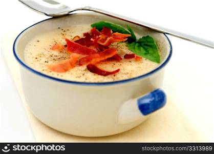 Potato Soup With Basil And Bacon. Potato soup topped with crisp bacon and fresh Basil leaves served in a rustic blue and white bowl
