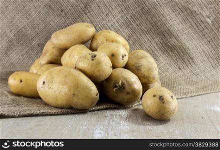potatoes and jute background on wooden table