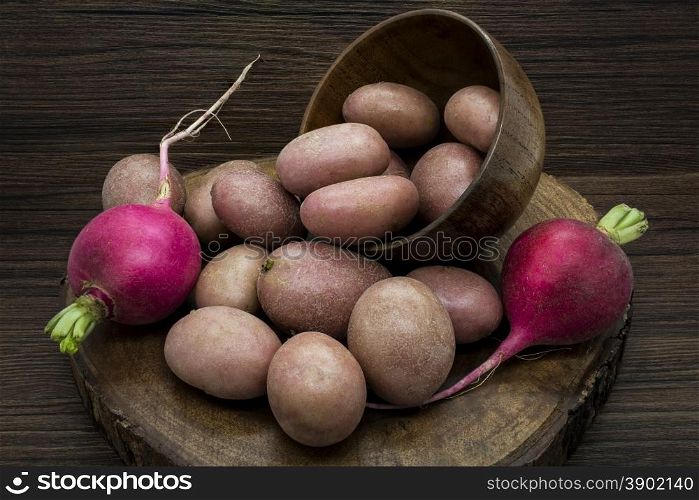 Potatoes and radishes on a rustic wooden background.