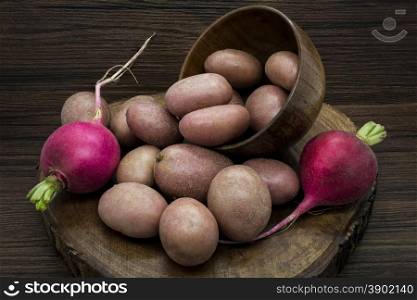 Potatoes and radishes on a rustic wooden background.