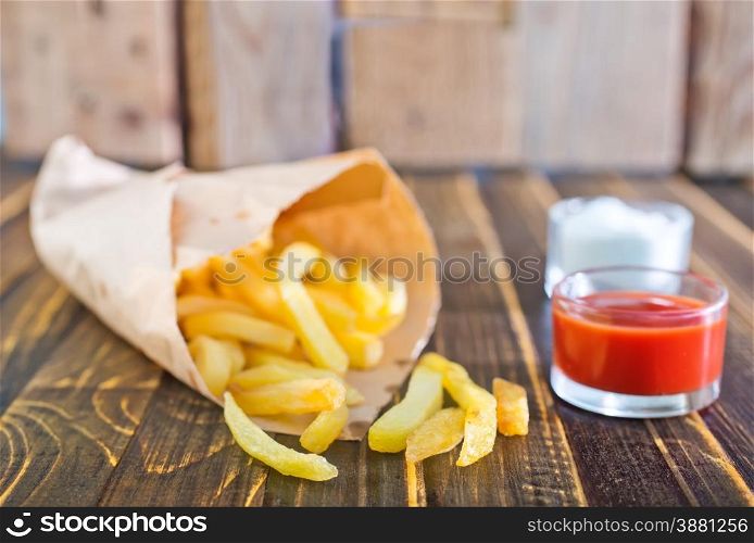 Potatoes fries in a little white paper bag on tomato sauce in bowl