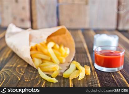 Potatoes fries in a little white paper bag on tomato sauce in bowl