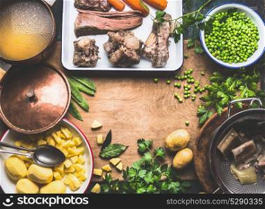 Potatoes soup with green pea and meat, cooking preparation on rustic kitchen table, top view, frame