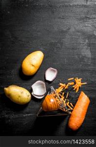 Potatoes with onions and carrots for soup. On a black wooden background.. Potatoes with onions and carrots for soup.