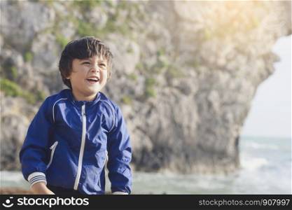 Potrait of happy kid boy smiling standing by the sea with blurry background, Chid playing in the Durdle Door beach in the weekend, Shot in Dorset, England, United Kingdom