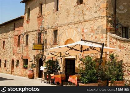 Potted plants and patio umbrellas in front of a building, Piazza Roma, Monteriggioni, Siena Province, Tuscany, Italy