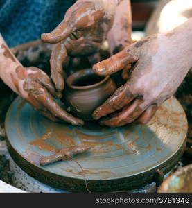 Potter&rsquo;s hands guiding child&rsquo;s hands to help him to work with the pottery wheel