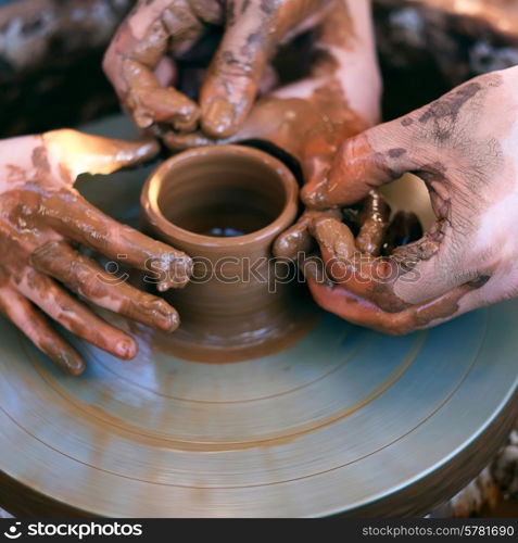 Potter&rsquo;s hands guiding child&rsquo;s hands to help him to work with the pottery wheel