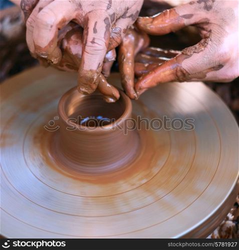 Potter&rsquo;s hands guiding child&rsquo;s hands to help him to work with the pottery wheel