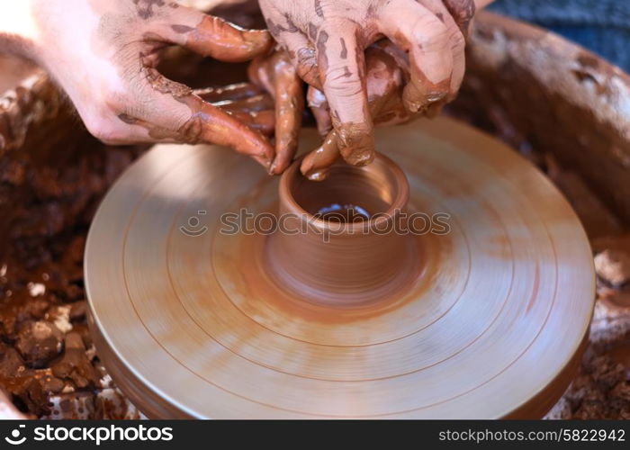 Potter&rsquo;s hands guiding child&rsquo;s hands to help him to work with the pottery wheel