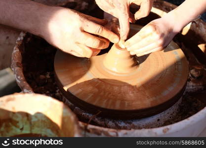 Potter&rsquo;s hands guiding child&rsquo;s hands to help him to work with the pottery wheel