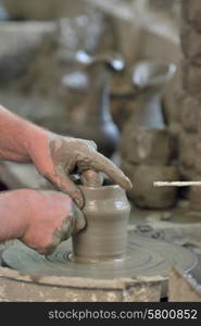 Potter&rsquo;s hands making a pot in workshop