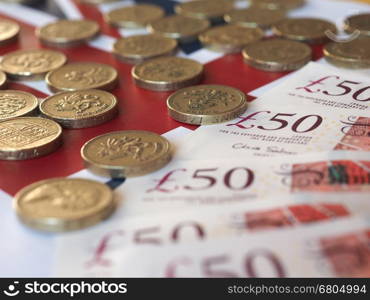 Pound coins and notes, United Kingdom over flag. Pound coins and banknotes money (GBP), currency of United Kingdom, over the Union Jack