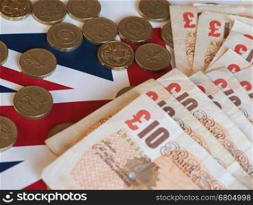 Pound coins and notes, United Kingdom over flag. Pound coins and banknotes money (GBP), currency of United Kingdom, over the Union Jack