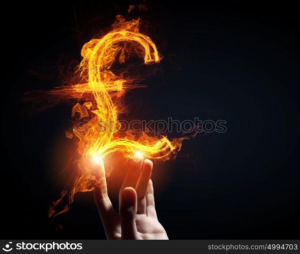 Pound currency concept. Burning pound sign in businessman palm on dark background