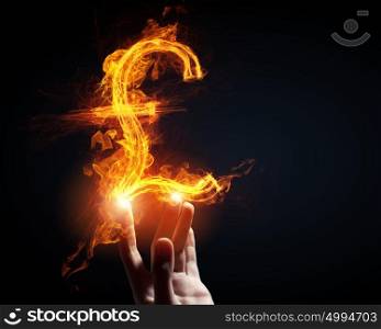 Pound currency concept. Burning pound sign in businessman palm on dark background