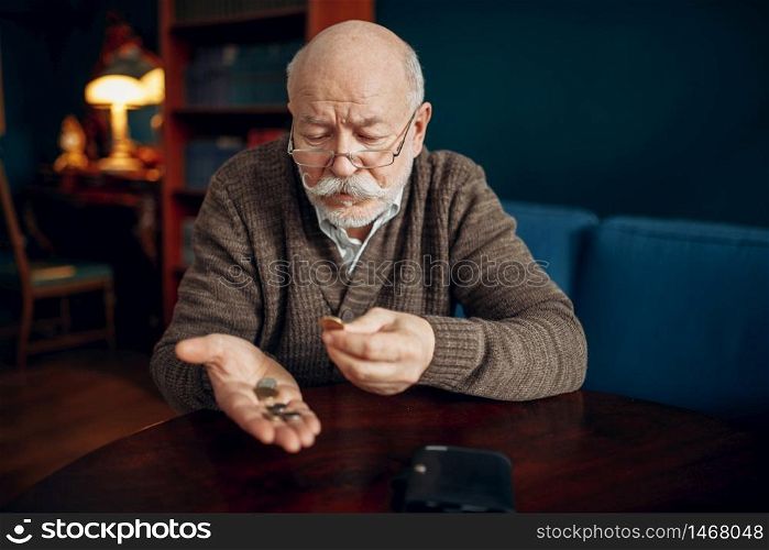 Pour elderly man holds some coins. Pour elderly man holds coins