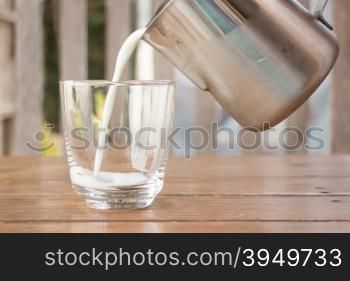 Pour milk from a pitcher into a glass, stock photo