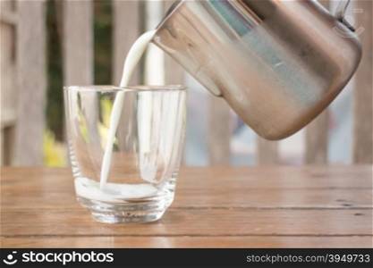 Pour milk from a pitcher into a glass, stock photo