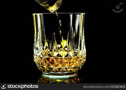 Pouring a glass of crisp golden whiskey from a bottle