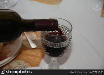 Pouring a glass of red wine on a dining table