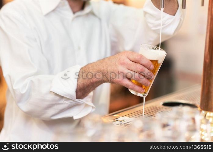 Pouring beer for client. Bartender pouring beer while standing at the bar counter .. Pouring beer for client. Bartender pouring beer while standing at the bar counter.