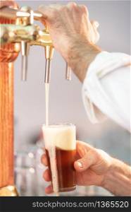 Pouring beer for client. Bartender pouring beer while standing at the bar counter .. Pouring beer for client. Bartender pouring beer while standing at the bar counter.