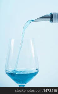 Pouring blue wine with splash and bubbles into a wine glass, close up. Blue Wine Pouring