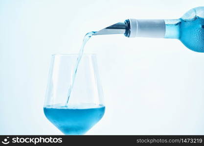 Pouring blue wine with splash and bubbles into a wine glass, close up. Blue Wine Pouring